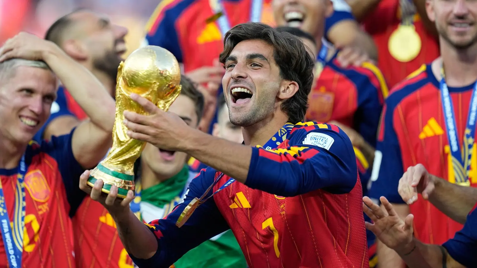 Ferran Torres celebrating with teammates, holding the World Cup trophy.