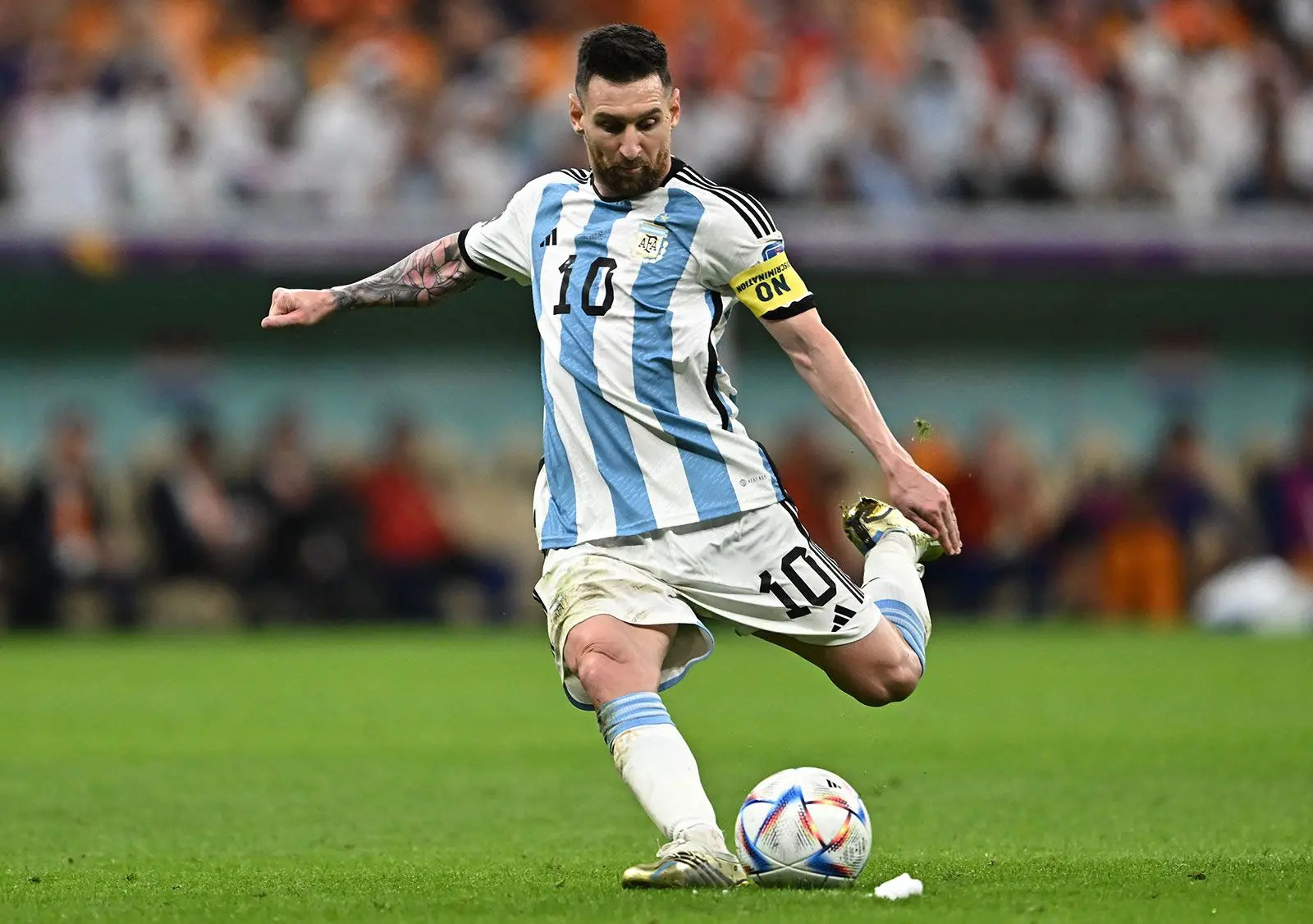 Lionel Messi in Argentina jersey kicking a soccer ball during a match.