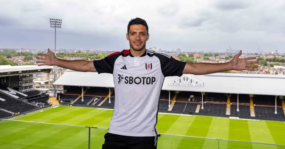 Raul Jimenez in Fulham FC kit at Craven Cottage stadium with arms outstretched.