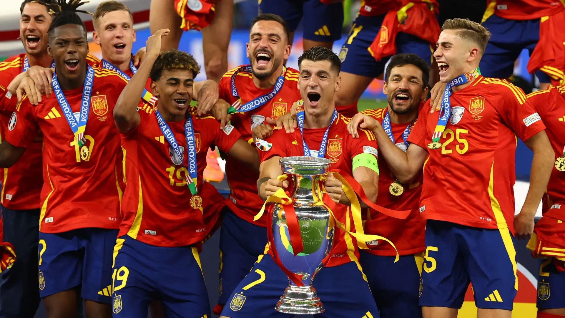 Spain national football team celebrating with a trophy and medals after a tournament victory.