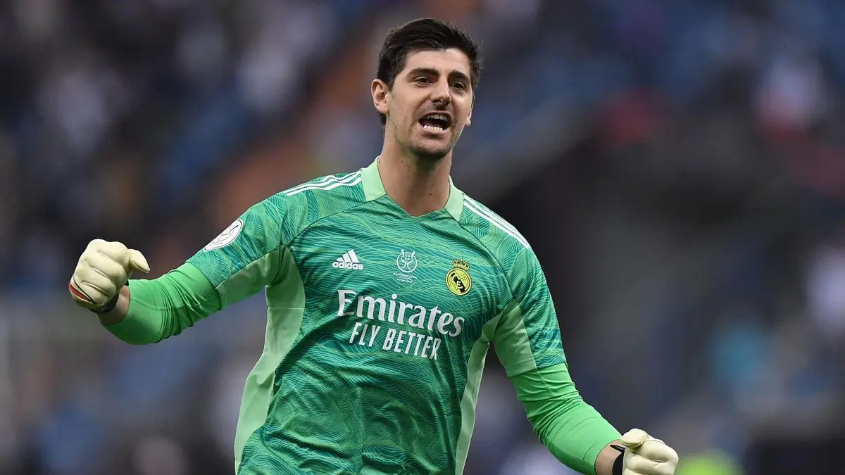 Thibaut Courtois celebrating in a green Real Madrid goalkeeper kit.