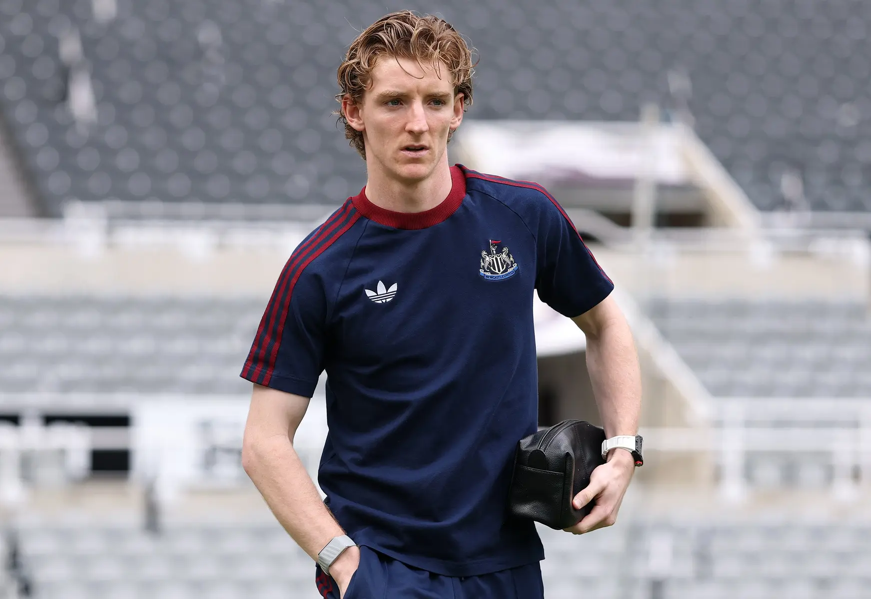 Anthony Gordon wearing a navy blue Newcastle United training shirt in a stadium