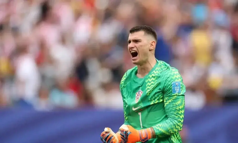 Dominik Livakovic shouting while wearing a green Croatia goalkeeper jersey and gloves during a match