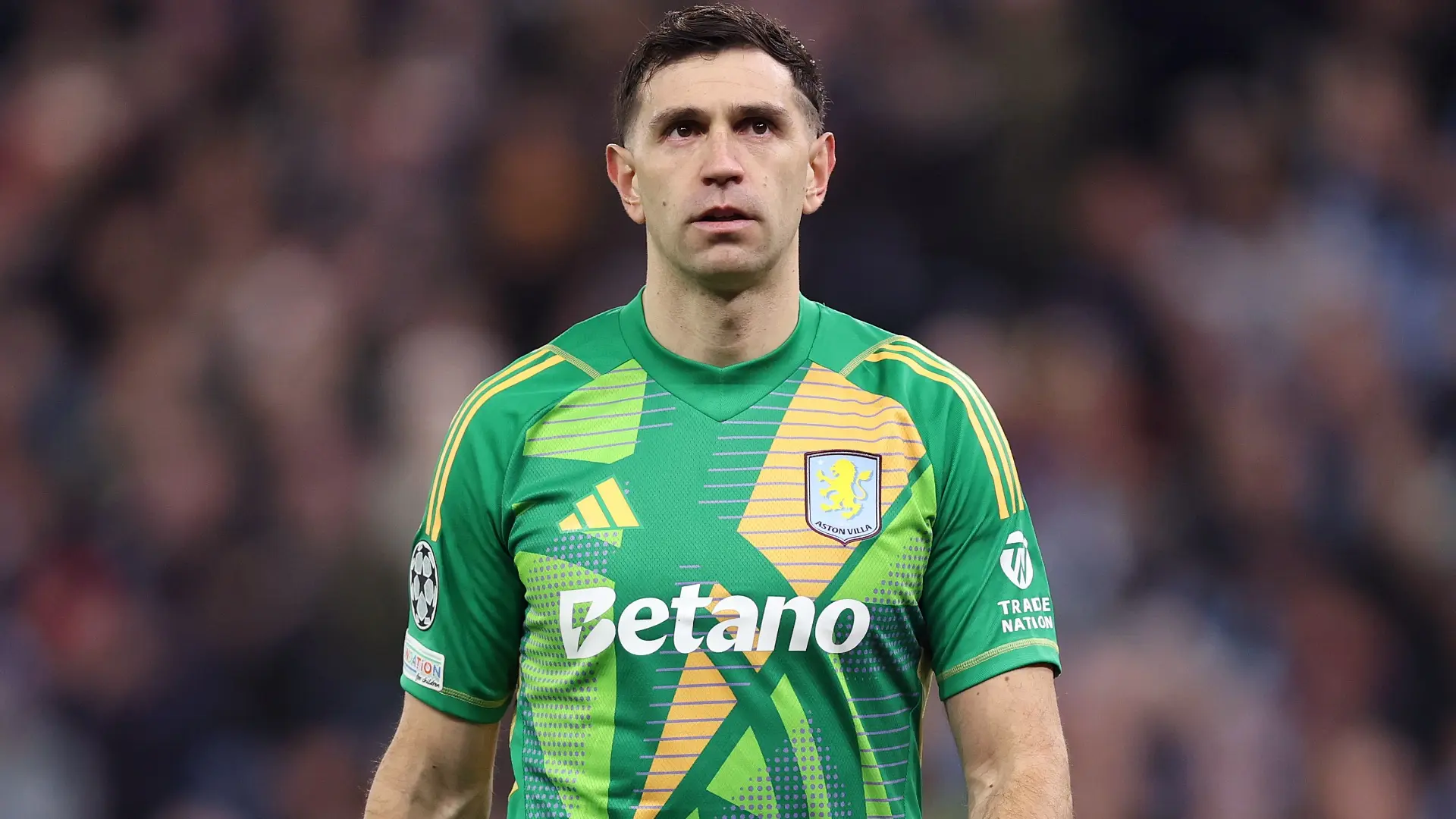 Emiliano Martinez wearing a green Aston Villa goalkeeper jersey with Betano sponsor logo