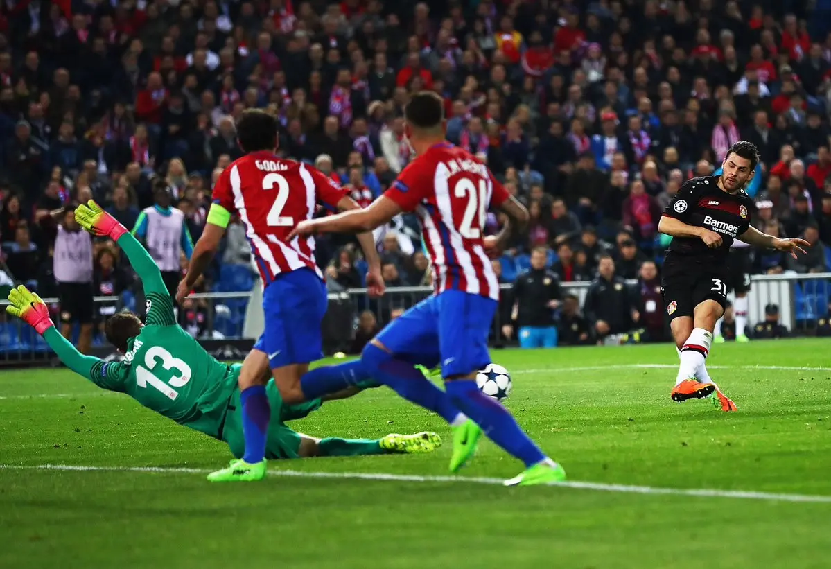 Atletico Madrid goalkeeper Jan Oblak diving to make a save against a Bayer Leverkusen player