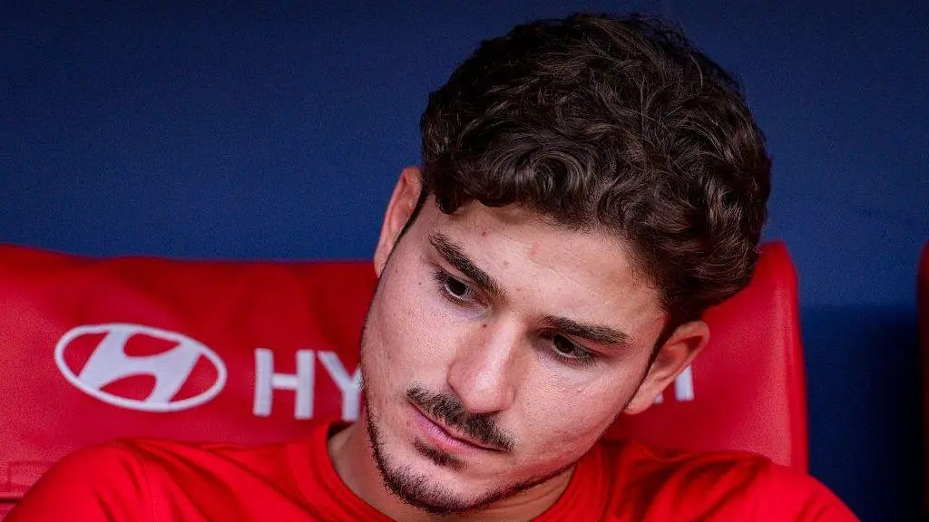 Close-up of Julian Alvarez wearing a red athletic shirt, looking downward with a serious expression