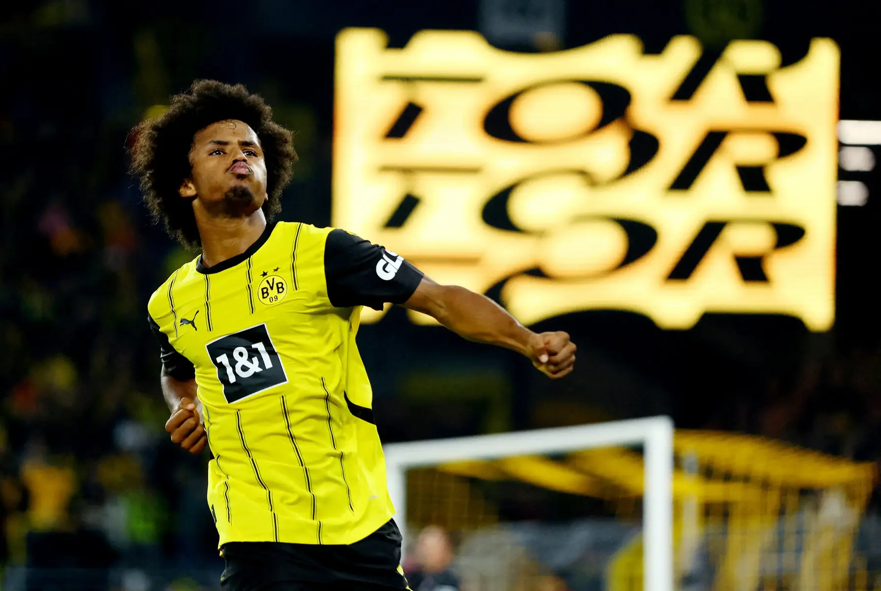Karim Adeyemi in a yellow Borussia Dortmund kit celebrating on the pitch during a match