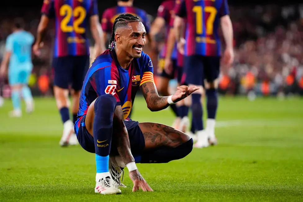 Raphinha of FC Barcelona celebrating while kneeling on the grass during a match