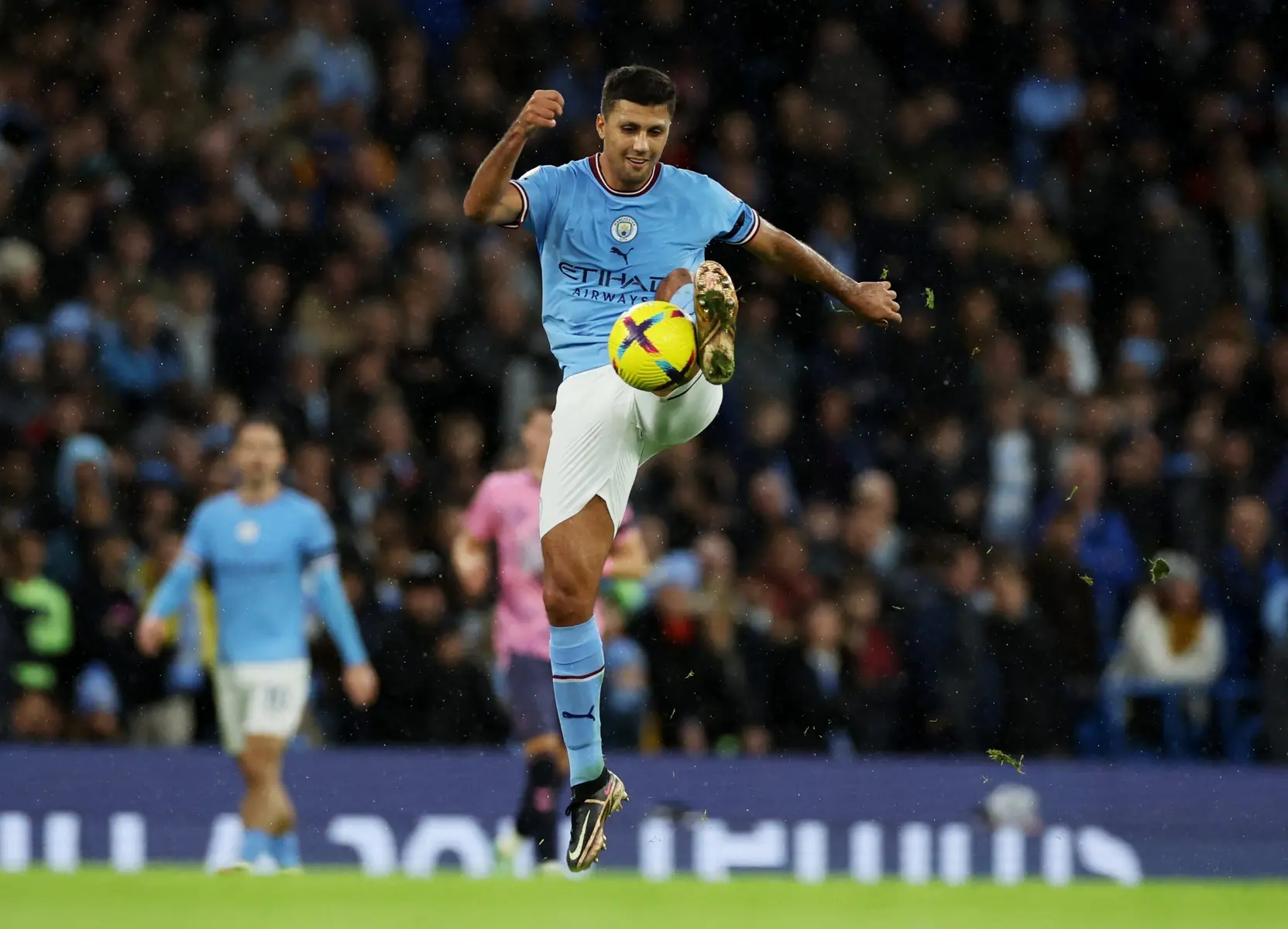 Manchester City midfielder Rodri controlling a football mid-air during a match.