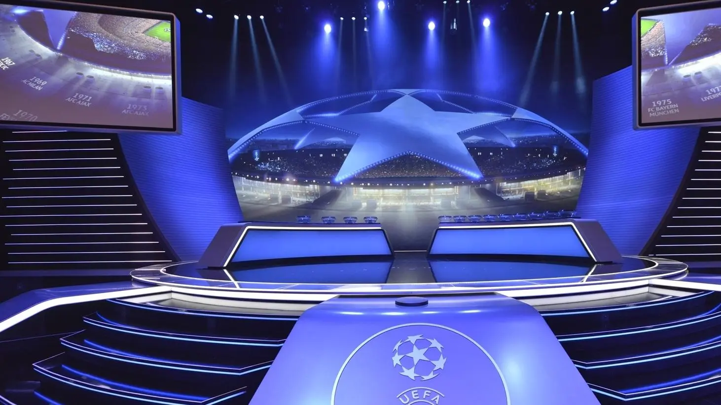 A high-tech blue stage set for the UEFA Champions League draw with large screens and the starball logo.