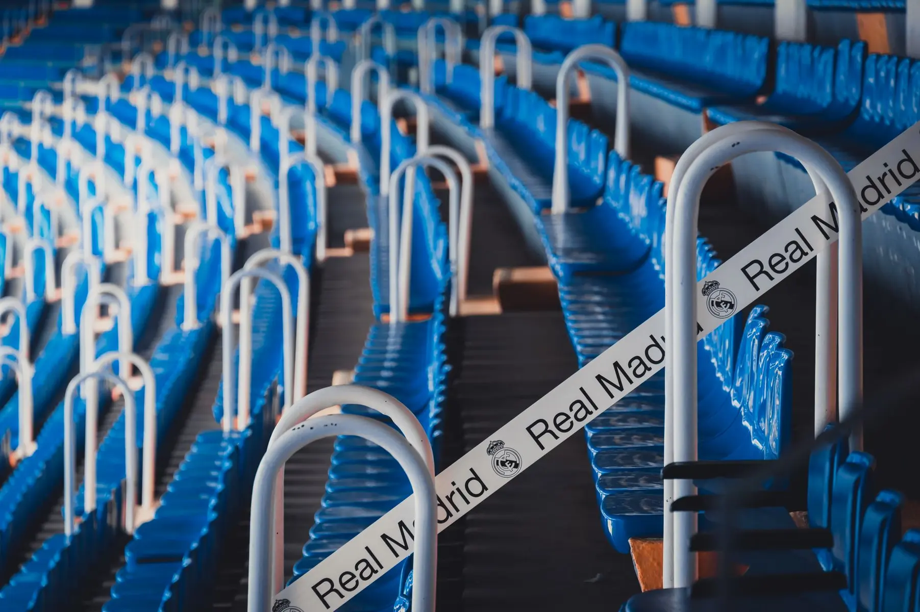 Rows of blue stadium seats with a Real Madrid branded ribbon across the railing